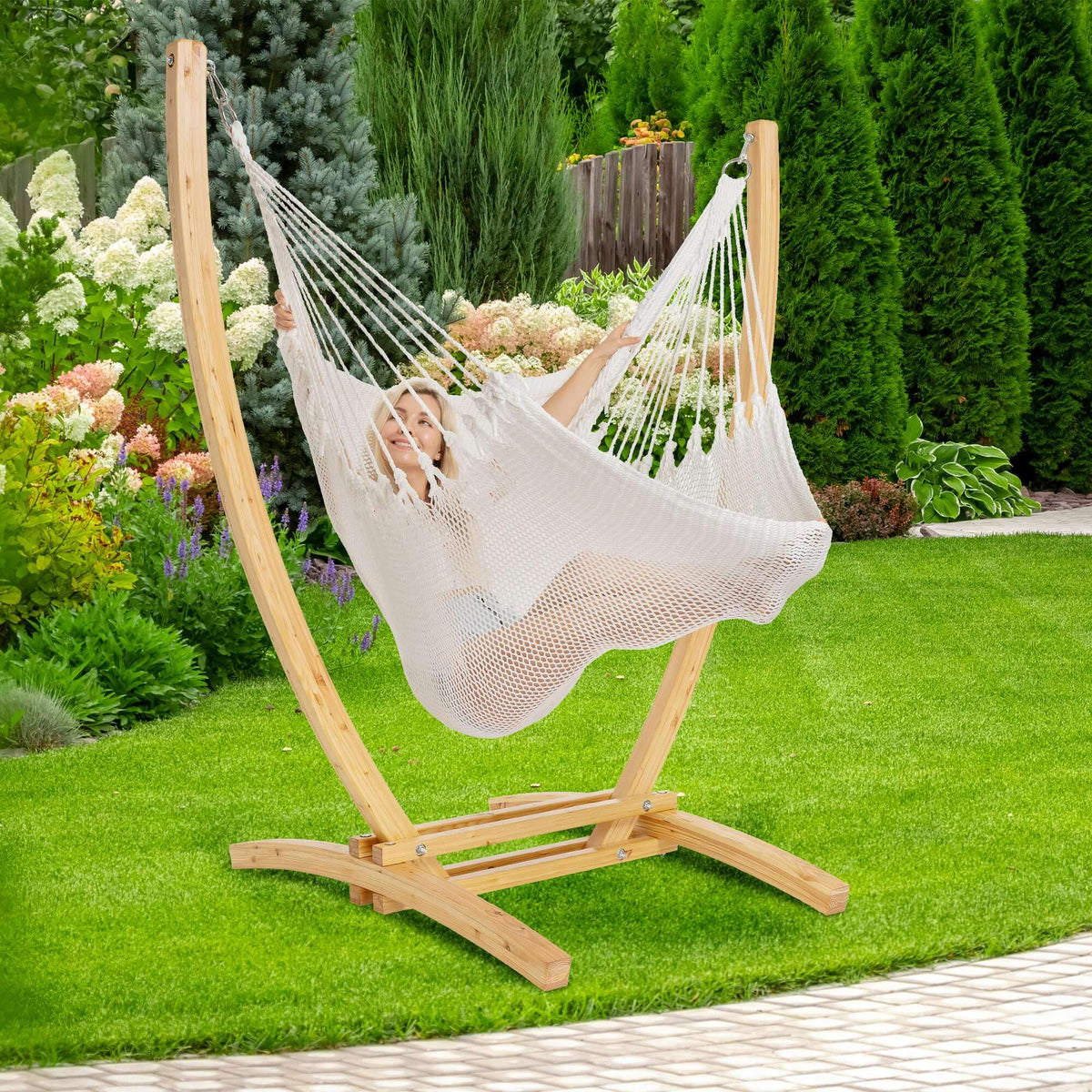 White Jumbo Caribbean Recliner on a wood arc stand in a backyard beside flowering hydrangeas