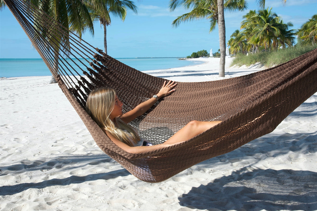 Woman reclining in the Mocha Jumbo Mayan Hammock on the beach, the deep bed cradling her