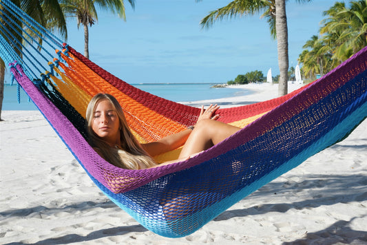Woman reclining in the Rainbow Jumbo Mayan Hammock, close view of the striped hand-woven bed