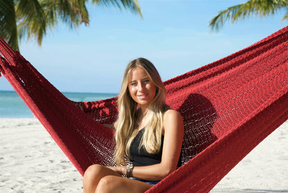 Close view of a woman sitting in the Red Jumbo Mayan Hammock, the hand-woven polyester bed framing her