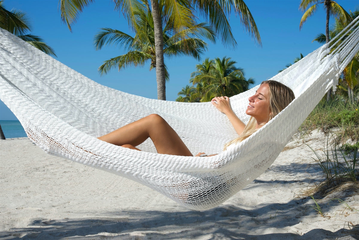 Woman reclining in the White Jumbo Mayan Hammock with palm trees behind