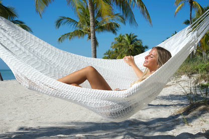 Woman reclining in the White Jumbo Mayan Hammock with palm trees behind