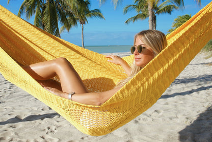 Close view of a woman in sunglasses reclining in the Yellow Jumbo Mayan Hammock