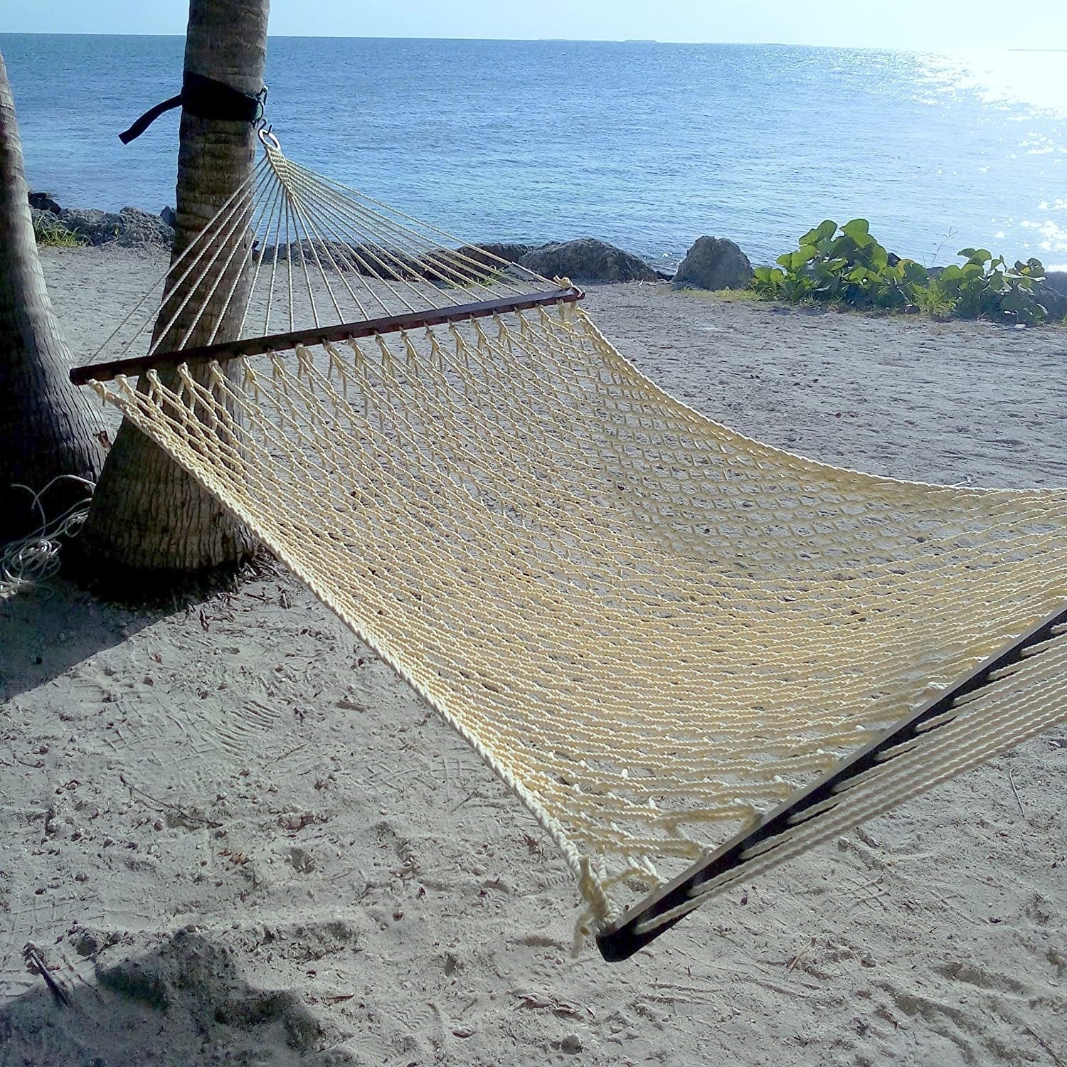 Cream Jumbo Rope Hammock strung from a palm tree on a sandy Caribbean beach.
