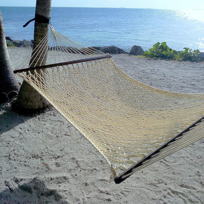 Cream Jumbo Rope Hammock strung from a palm tree on a sandy Caribbean beach.