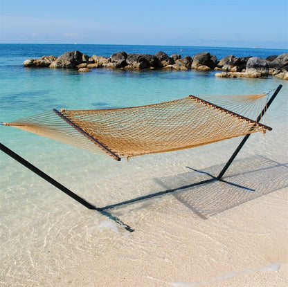 Tan Jumbo Rope Hammock on a black Tri-Beam hammock stand at the water's edge.