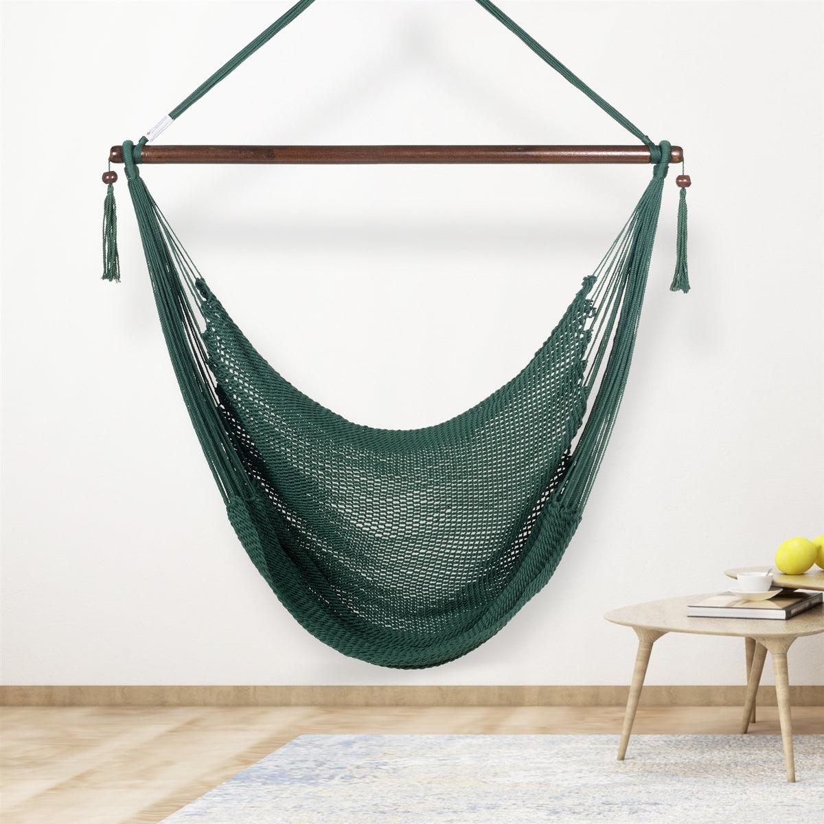 Green Large Caribbean Hammock Chair hanging indoors beside a small round side table against a cream wall