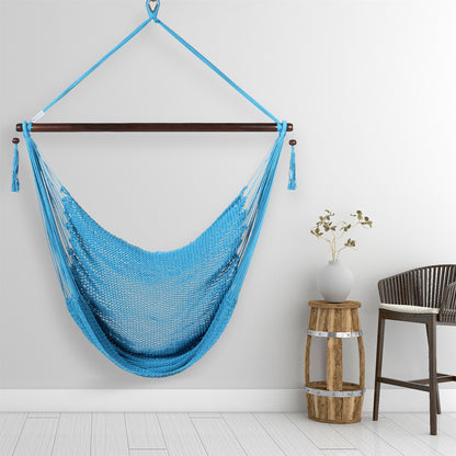 Light blue Large Caribbean Hammock Chair hanging beside a barrel side table and rattan stool against a pale grey wall