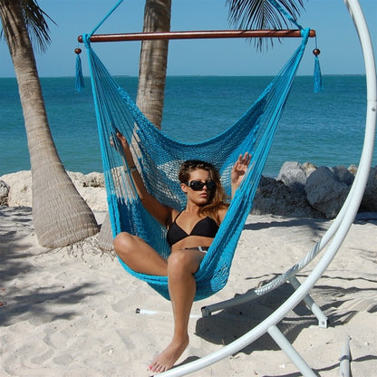 Woman seated in a light blue Large Caribbean Hammock Chair on a white arc stand on a sandy beach