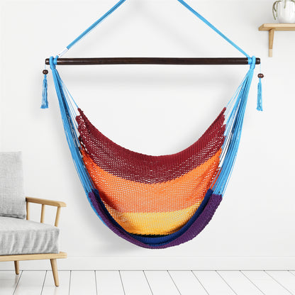 Rainbow Large Caribbean Hammock Chair hanging indoors beside a pale wood armchair against a white wall