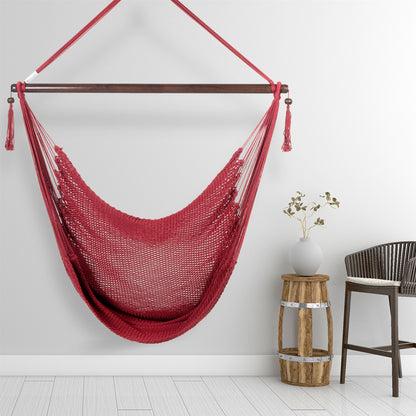 Red Large Caribbean Hammock Chair hanging beside a barrel side table and rattan stool against a pale grey wall