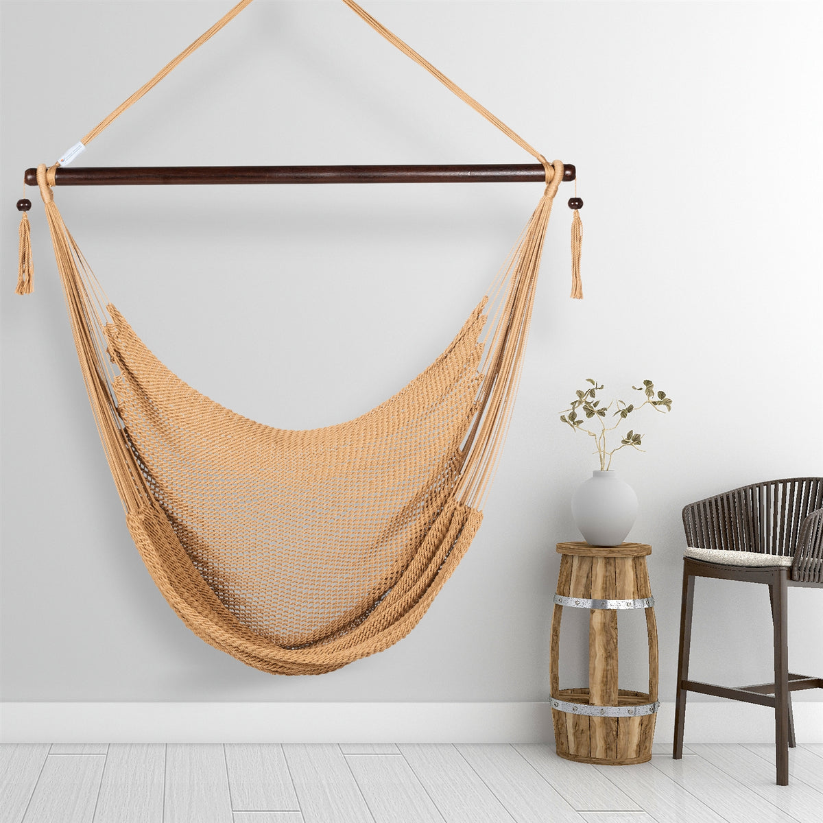 Tan Large Caribbean Hammock Chair hanging beside a barrel side table and rattan stool against a pale grey wall