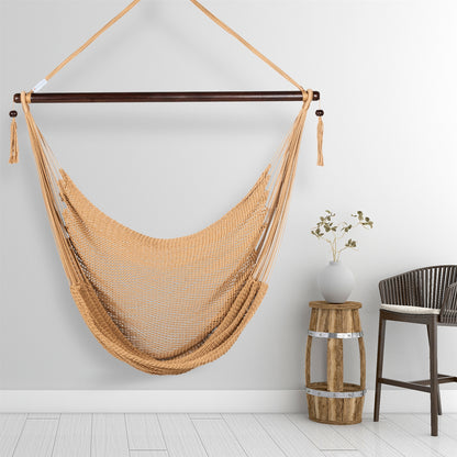 Tan Large Caribbean Hammock Chair hanging beside a barrel side table and rattan stool against a pale grey wall
