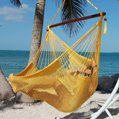 Woman reclining in a yellow Large Caribbean Hammock Chair under palm trees on a white sand beach